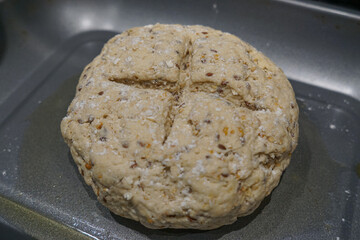 Unbaked round loaf of homemade bread formed on a baking tray before being placed in the oven.
