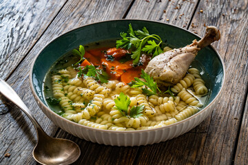 Broth - chicken soup with noodles and carrots on wooden table	