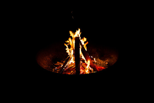 Feu de bois dans un brasero en fer dans la nuit avec des flammes qui dansent autour des b&ucirc;ches de bois