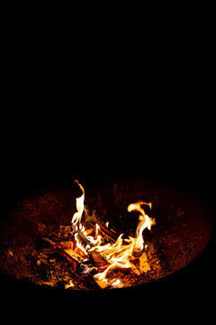 Gros plan d'un feu de bois avec des flammes et des b&ucirc;ches de bois dans un brasero en fer, fond noir