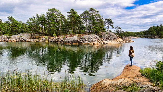 Wanderin beobachtet auf einer Felskuppe die gegen&uuml;berliegende Sch&auml;reninsel im Naturreservat Stend&ouml;rren in Schweden