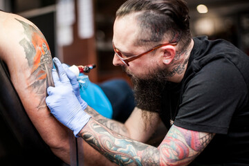 Tattoo artist tattooing an arm