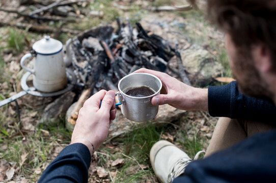 Man drinking coffee at campfire