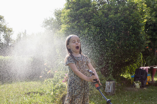 Girl splashing with water in garden