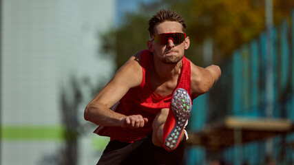Focused athlete jumping hurdle with determination and intensity on track. Concept of focus, ambition, competitive drive for sports branding, athletic campaigns, and motivational posters.