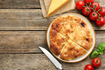 Delicious Megrelian khachapuri, knife and products on wooden table, flat lay. Space for text