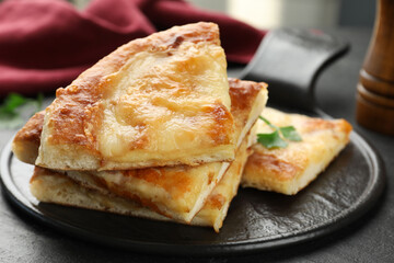 Pieces of delicious Megrelian khachapuri on black table, closeup