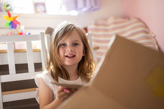 Kid smiling while crafting and painting a box in a creative room