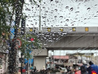 Raindrops on a car window with a blurred street scene in the background