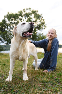 Smiling girl with labrador retriever dog outdoors in summer showing happiness