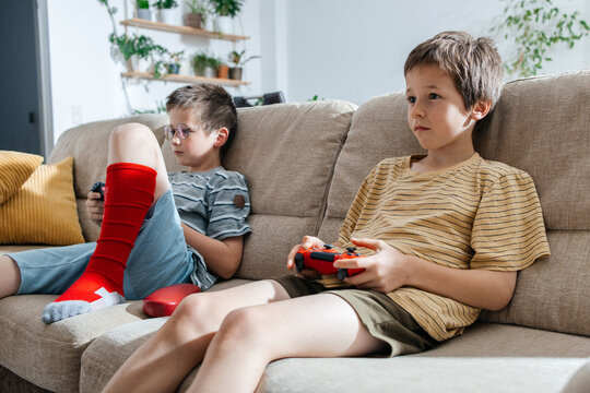 Children playing video game together on sofa in living room