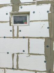 White wall insulated with polystyrene foam, with a window in the middle