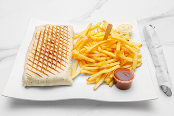 Tacos lyonnais &ndash; sp&eacute;cialit&eacute; fran&ccedil;aise de street food halal, garni de viande, frites et sauce, pr&eacute;sent&eacute; sur une table de restauration rapide