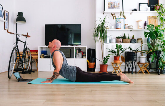 Man practicing cobra pose in living room at home