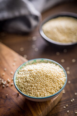 Roasted sesame seeds in bowl on wooden table.
