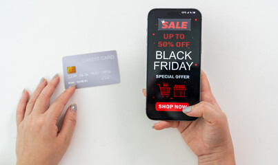 Person using app shop online holding smartphone with Black Friday sale ad and credit card ready for online payment, e-commerce promotions, digital marketing, online shopping and mobile transactions