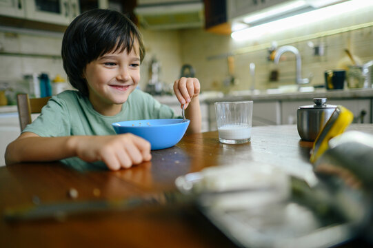 Smiling child eating breakfast at kitchen table in the morning