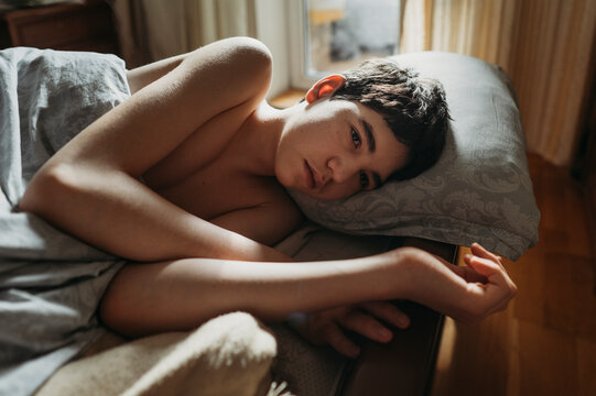 Sad boy lying on bed at home