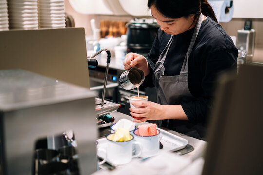 Young barista making coffee in commercial kitchen