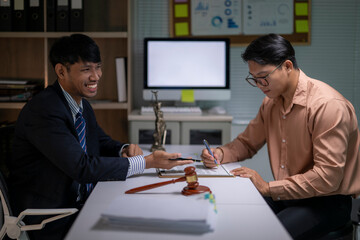 Two men are sitting at a desk, one of them is smiling