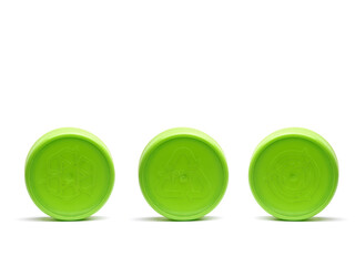 Three green plastic caps with different recycle symbols embossed shot on white