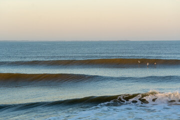 Tranquil ocean scene featuring evenly breaking waves under the gentle glow of early morning light. 