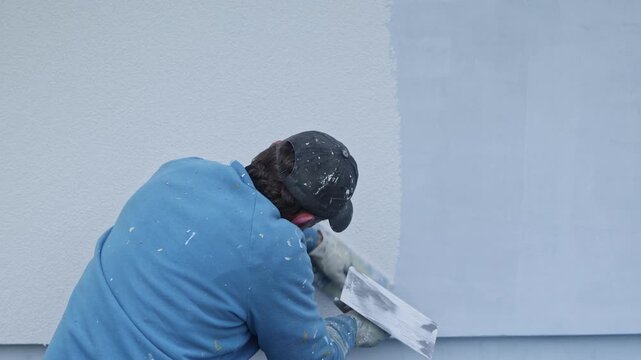 Construction worker plastering exterior wall with trowel