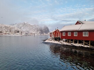 Fototapeta premium Lofoten Islands, Reine, Norway and Hamnoy fishing village with red rorbuer houses in winter sunset landscape 