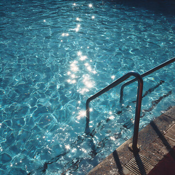 Handrail Leading To Sparkling Blue Pool Water
