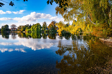 Autumn Reflection On Wesslinger See In Bavaria: Serene Landscape With Colorful Trees, Blue Sky, And...