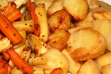 Close up of roasted vegetables crsipy potatoes parsnip and carrots side dish for Sunday roast dinner