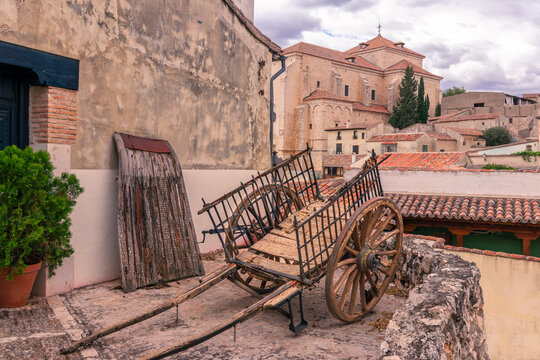 paisaje urbano de un viejo carro junto a un trillo de labranza en Chinch&oacute;n, Madrid, Espa&ntilde;a con la poblaci&oacute;n y la iglesia de Santa Mar&iacute;a la Mayor