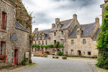 Picturesque view of the granite stone main square of the medieval town commune of Locronan, with flowers and plants in the Finistere department, Brittany region, France