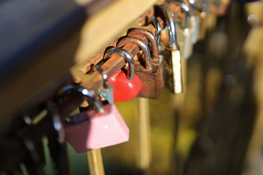 Close-up of love locks on bridge railing in sunlight