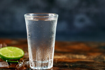 Vodka. Shots, glasses with vodka with ice and lime on gray background