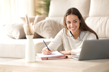 Happy student taking notes watching online course