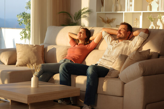 Happy couple relaxing sitting on a sofa at sunset at home