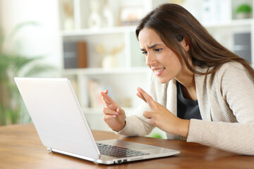 Hopeful woman crossing fingers checking laptop waiting for result