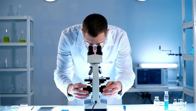 Male Scientist Examining Samples Under Microscope in Laboratory Setting