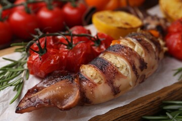 Tasty stuffed squid, rosemary and tomatoes on table, closeup