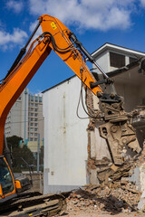 Demolition of a building using heavy machinery in an urban environment on a sunny day
