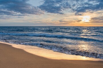 Colorful sunset viewed from the sea beach with soft waves