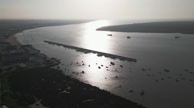 Aerial footage flying over a wide river in southern Spain, filled with boats and yachts, lively maritime activity.