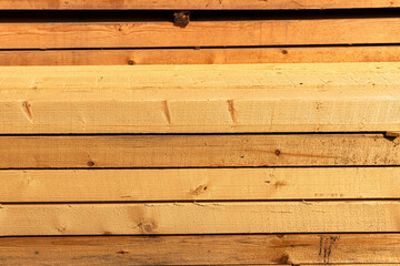 Stacked timber planks creating a rustic textured background. Raw wood material good for construction, carpenters, or projects
