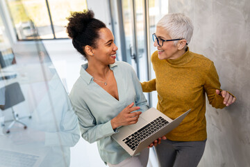 Mentorship and diversity in a modern office as colleagues share a laptop for team collaboration
