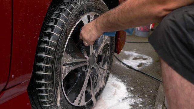 Cleaning back of car wheel spokes with blue microfibre cloth
