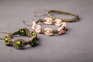 Some beaded bracelets from macrame yarn on grey background. Soft focused shot. Friendship wristbands.