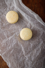 tender yellow macaroons with buttercream, salted caramel or condensed milk on paper, wooden background. Copy space, top view
