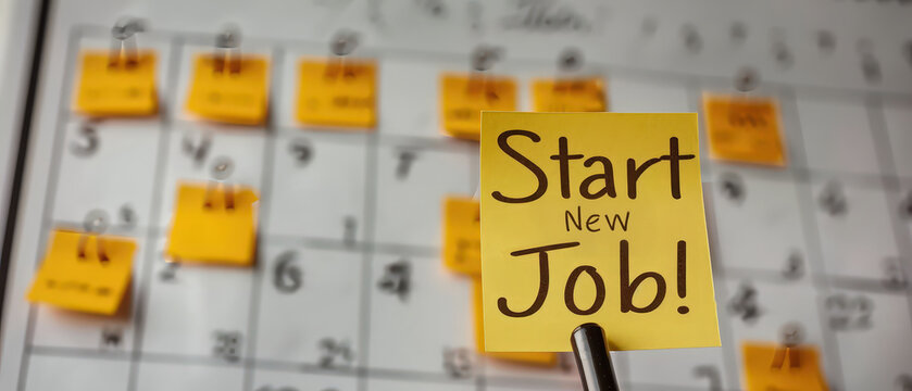 Yellow sticky note with Start New Job message pinned in front of a calendar, highlighting an important career milestone or reminder.