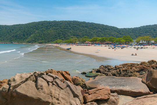 Guaiuba Beach, Guaruja SP, Brazil. Sunny day over the small bay with tranquil sea. Image of leisure and tourism on the Sao Paulo coast. Hills covered in Mata Atlantica vegetation frame the view.